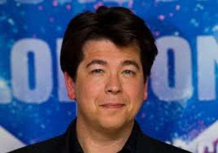 Michael McIntyre in black shirt poses at an event.